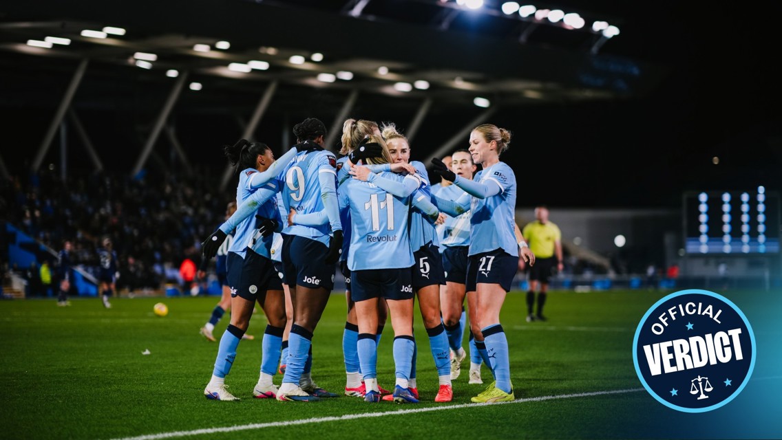 Women's soccer team with blurred faces celebrating on the field, wearing light blue jerseys with numbers and sponsor logos.