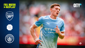 A Manchester City player in light blue kit during a match against Arsenal with logos and 'City+' branding on the sides.