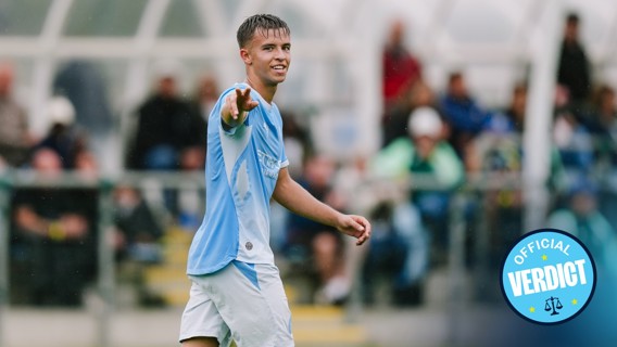 A football player pointing towards the camera while wearing a light blue and white kit, with a badge that says 'Official Verdict'.