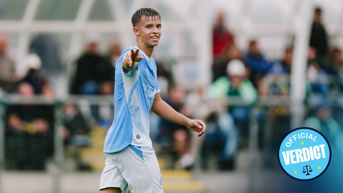 A football player pointing towards the camera while wearing a light blue and white kit, with a badge that says 'Official Verdict'.