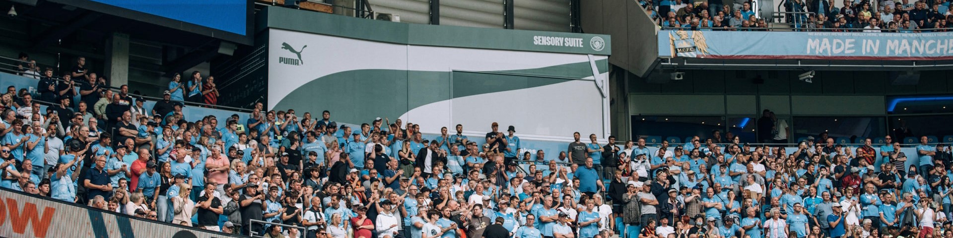 Crowd of spectators at Etihad Stadium during Manchester City vs Crystal Palace match, with FIFA23 EA Sports advertisement and Crystal Palace logo visible on screens.