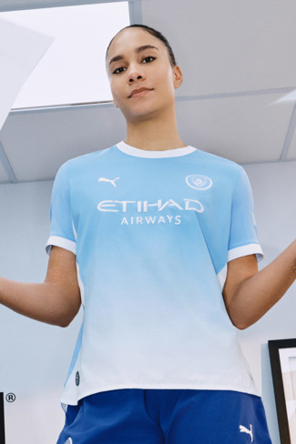Person wearing light blue Manchester City football jersey with Etihad Airways sponsor and Puma logo.
