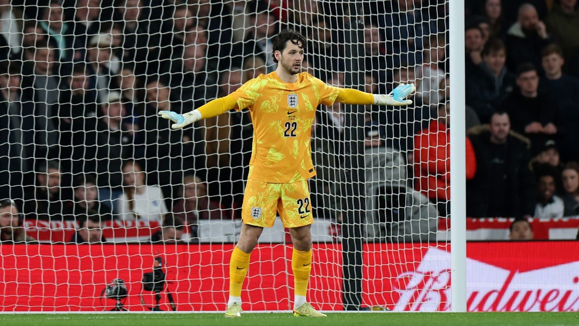 A football goalkeeper stands in front of the goal wearing a yellow kit with the number 22.