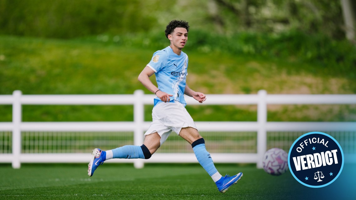 Blurred image of a football player running on a pitch wearing a Manchester City kit, with a badge showing 'Official Verdict'.