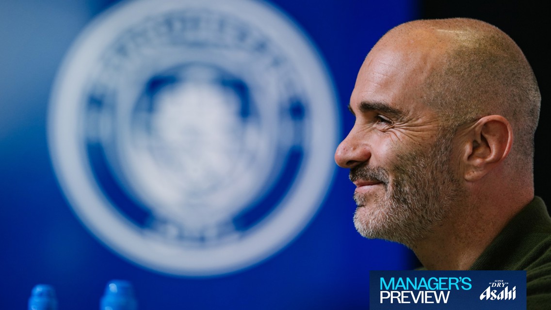 A person with a shaved head and beard is smiling in profile view. The background features a blurred circular logo. Text in the bottom corner reads 'MANAGER'S PREVIEW' and 'Super Dry Asahi'.