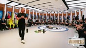 A group of athletes sits in a modern locker room with personalized spaces, surrounded by equipment. A sign displays 'Adobe Women's FA Cup Winners 2026'.
