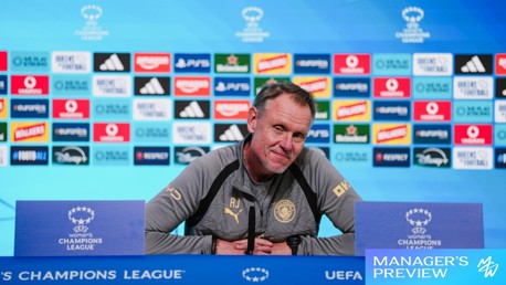Person at UEFA Women's Champions League press conference podium with sponsor logos in the background.
