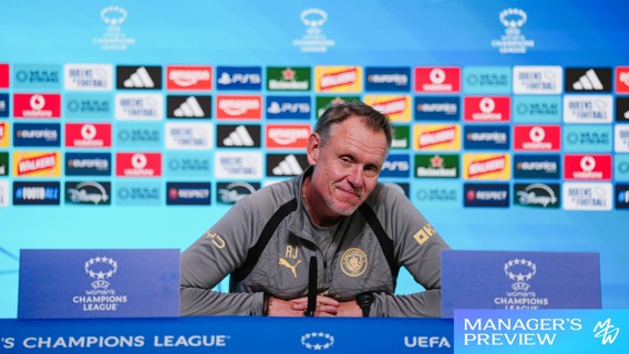 Person at UEFA Women's Champions League press conference podium with sponsor logos in the background.