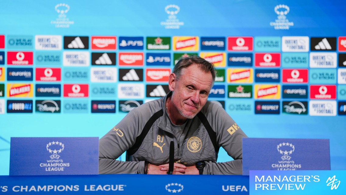 Person at UEFA Women's Champions League press conference podium with sponsor logos in the background.