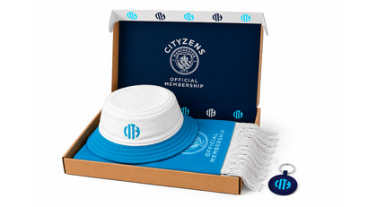 Manchester City membership pack containing a bucket hat, scarf, and keychain in a branded box.
