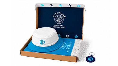 Manchester City membership pack containing a bucket hat, scarf, and keychain in a branded box.