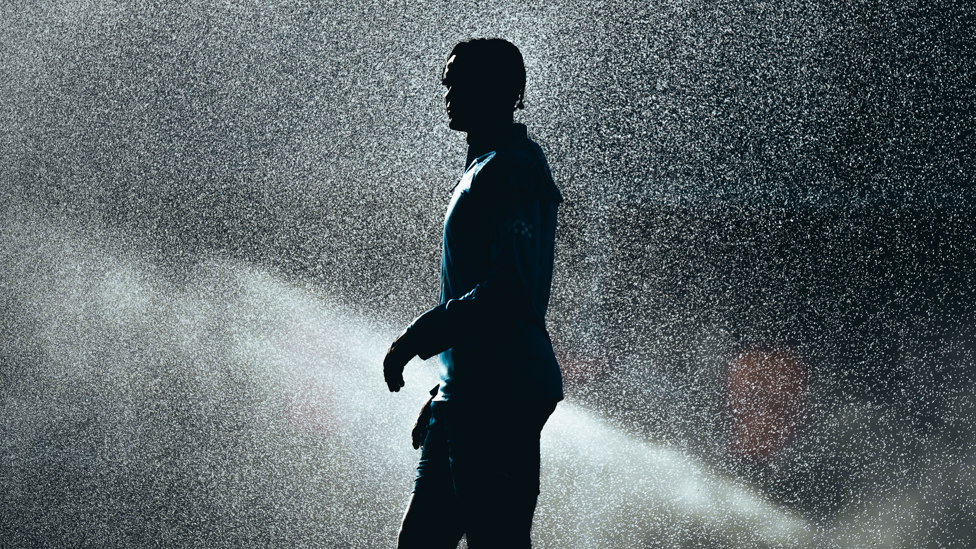 SUNNY SILHOUETTE : Akanji stands in front of the sprinklers