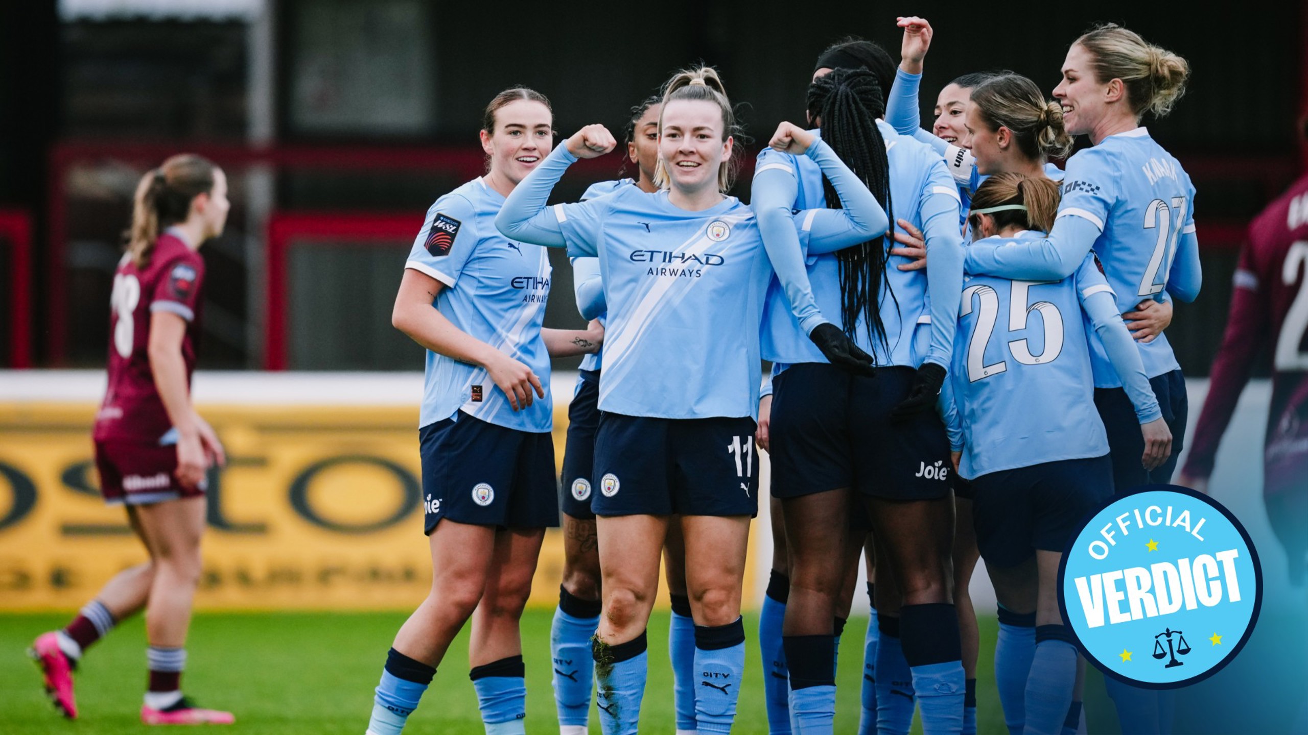 Manchester City Women's team celebrating a goal during a match, wearing light blue jerseys. A single opponent in a maroon kit is visible in the background.