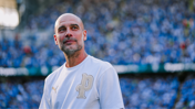 A person in a white PUMA shirt with a letter 'P' on it, standing in a stadium with a crowd in the background.