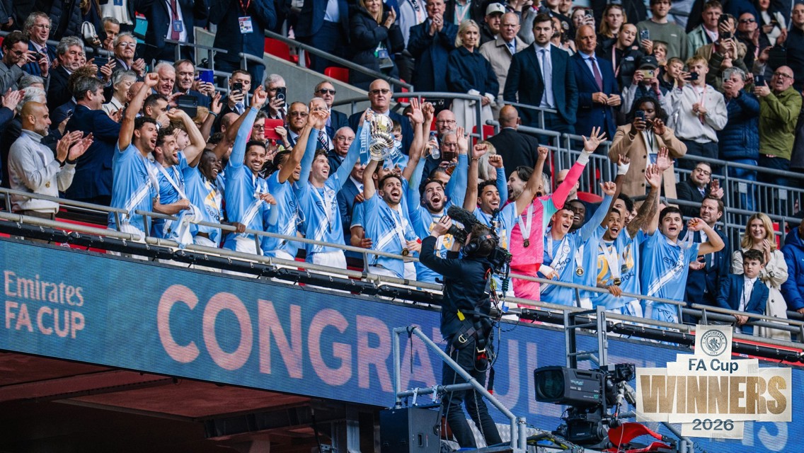 Manchester City celebrating their FA Cup win in 2026 with players lifting the trophy wearing light blue jerseys.