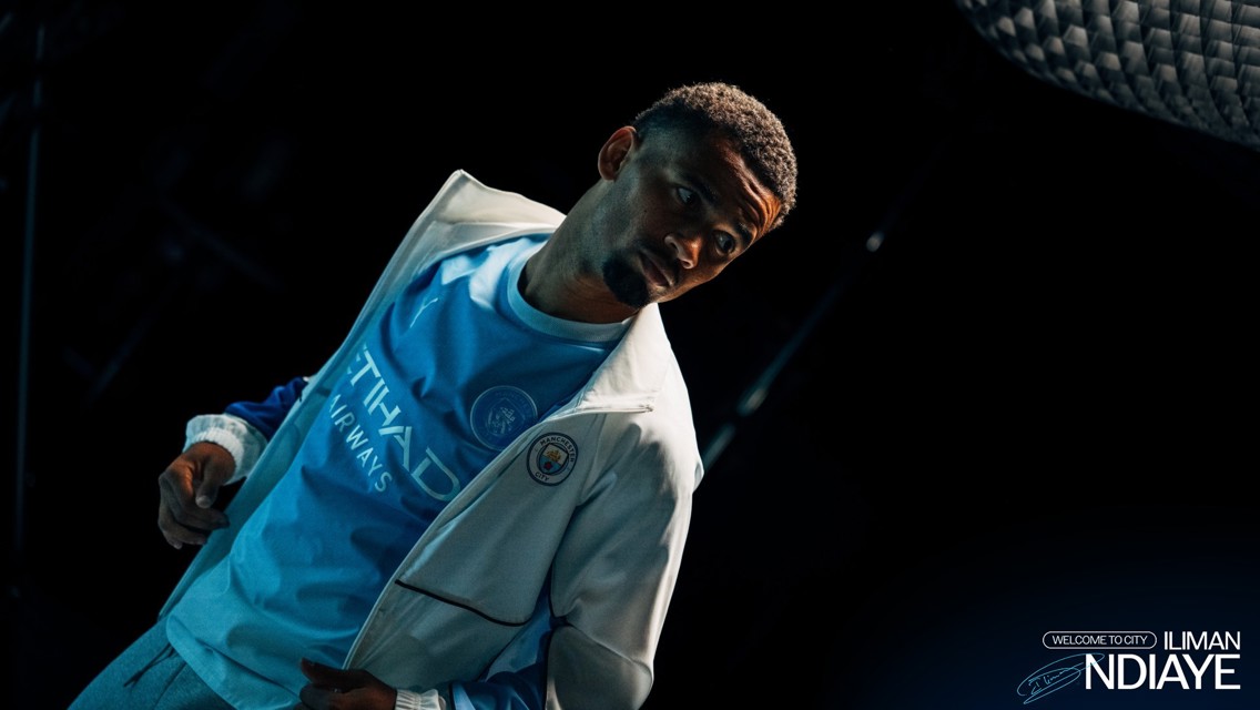 Person wearing Manchester City shirt with Etihad Airways logo, accompanied by text welcoming Iliman Ndiaye.
