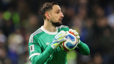 A goalkeeper wearing a green Adidas jersey holding a soccer ball during a match.