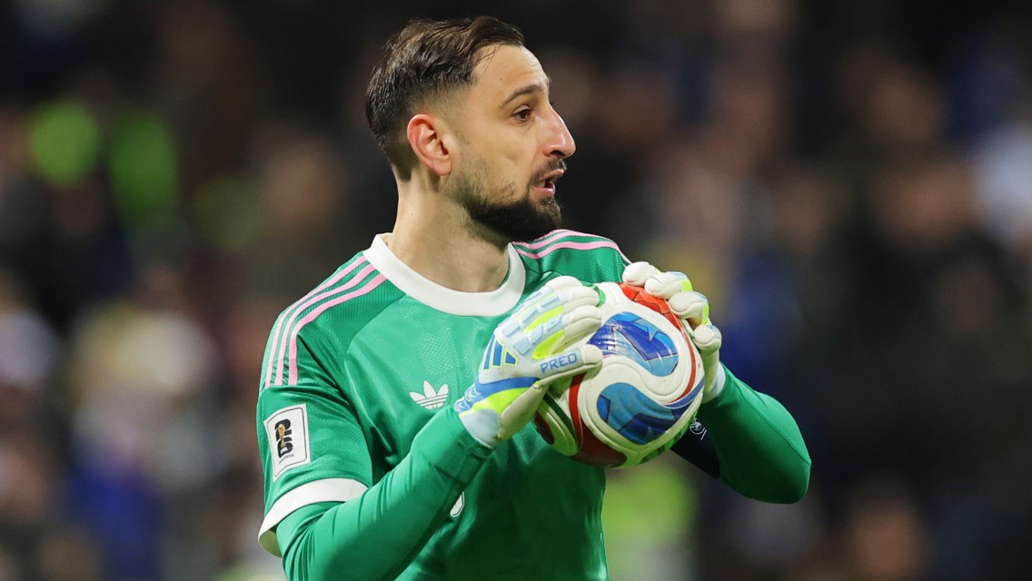 A goalkeeper wearing a green Adidas jersey holding a soccer ball during a match.