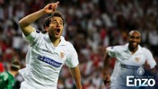A soccer player celebrating a goal in a white jersey with the Manchester City logo. Another player in the background is smiling and cheering.