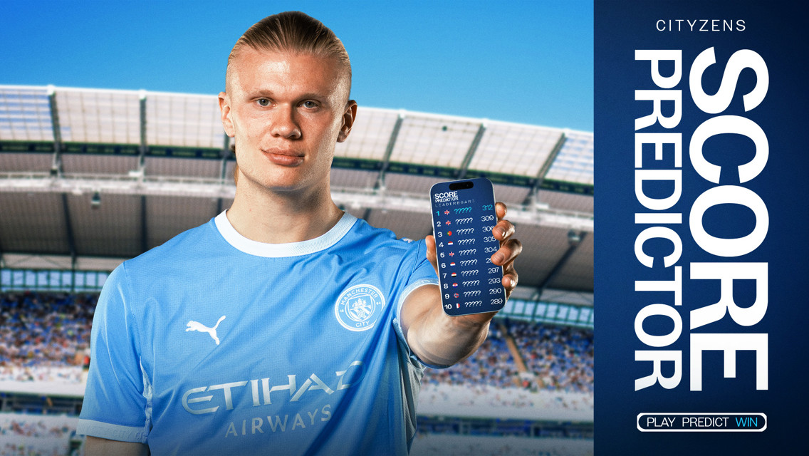 A football player in a Manchester City jersey holding a phone displaying a leaderboard of a score predictor game. The background features the Etihad Stadium.