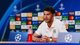A person in a Manchester City polo speaking at a UEFA Champions League press conference with sponsor logos in the background.