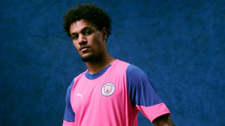A Manchester City player wearing the pink and blue kit made by Puma, featuring the Manchester City crest and Puma logo.