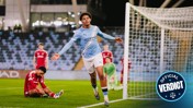 Football player in a blue Manchester City kit celebrates near the goal, while opposing players in red kits are nearby.