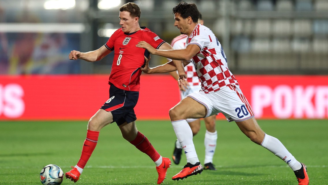 Two soccer players in action during a match. One player is wearing a red England kit, and the other is in a white and red Croatia kit.
