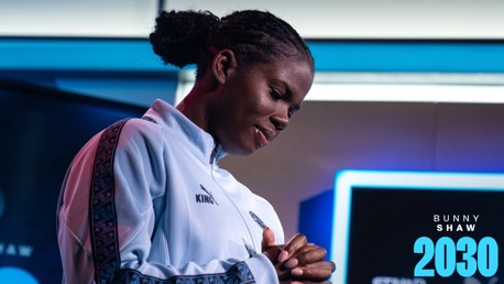 Person in sports tracksuit with logo, hands clasped, blurred face, text 'Bunny Shaw 2030' in corner.