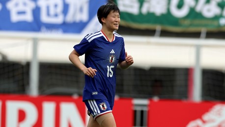 A football player wearing a Japan national team jersey, number 15, running on the field with a blurred background.