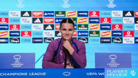 A person in a purple uniform sits at a press conference table with a UEFA Women’s Champions League logo. Behind are sponsor logos including Adidas, Heineken, PayPal, and Disney.