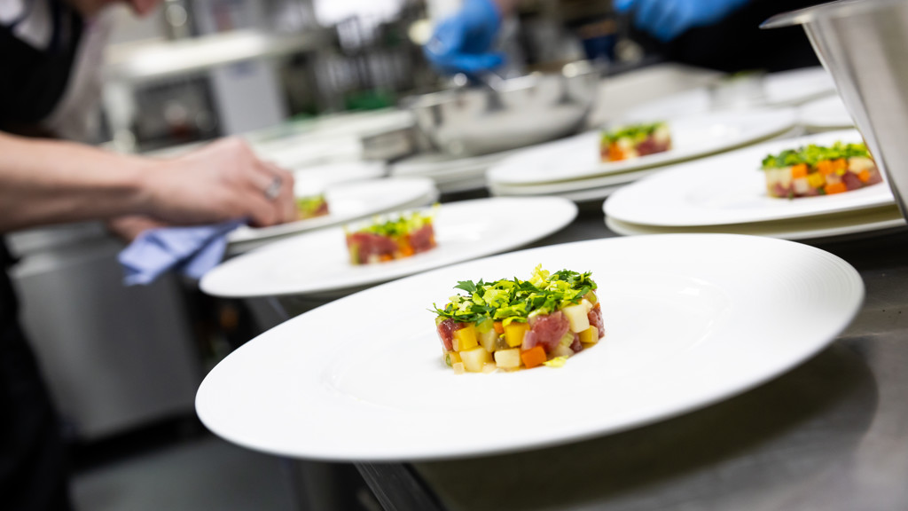 Chefs plating gourmet dishes with precision in a fine-dining kitchen.