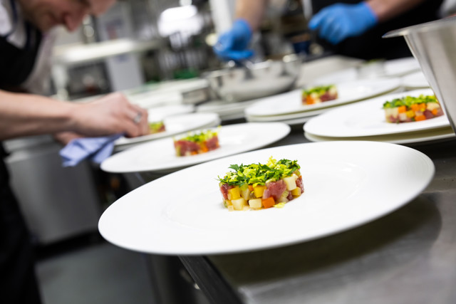 Chefs plating gourmet dishes with precision in a fine-dining kitchen.
