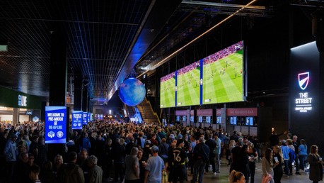 Large crowd at Co-op Live venue watching a sports event on big screens with multiple bars and signs around.