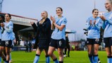 Manchester City women's football team players clapping on the field. They are wearing light blue jerseys with the Manchester City logo.