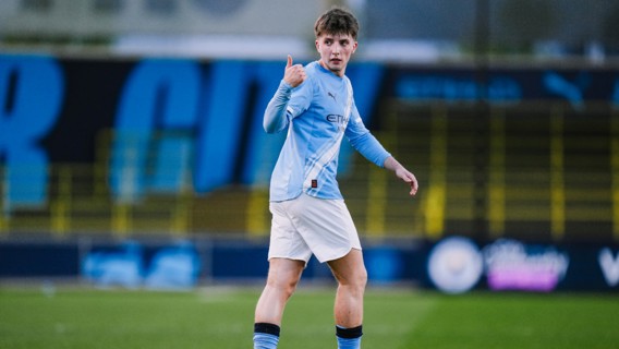 A football player in a Manchester City kit giving a thumbs up on the field.