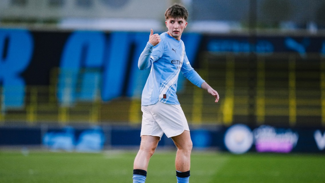 A football player in a Manchester City kit giving a thumbs up on the field.