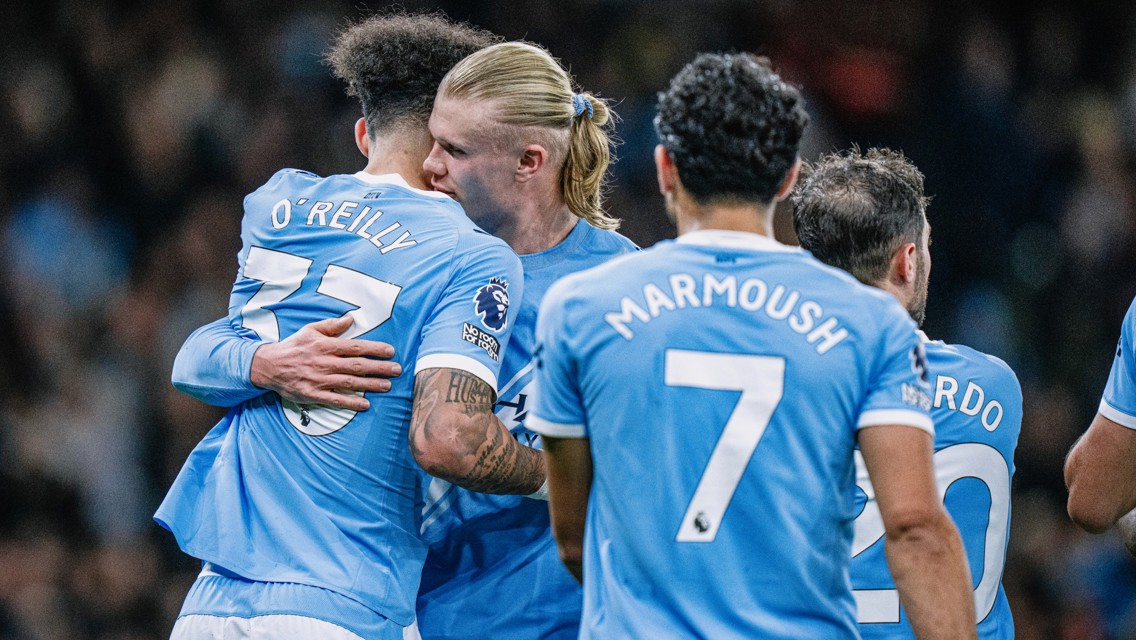 Manchester City players wearing blue jerseys celebrating a goal, with visible names O'Reilly, Marmoush, and Ricardo.