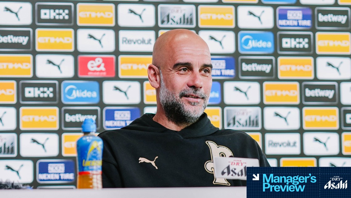 A person is speaking at a press conference with Manchester City sponsors like Etihad and Puma in the background.