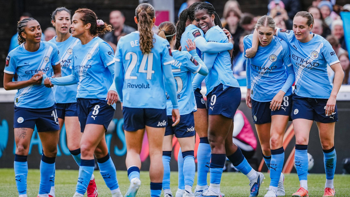 Manchester City Women's team celebrating on the field in blue jerseys during a match.