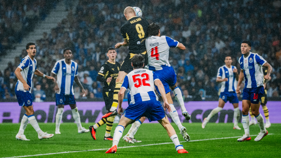 Soccer match with players from Borussia Dortmund in black and Manchester City in yellow kits, and FC Porto in blue-white kits competing on the field.
