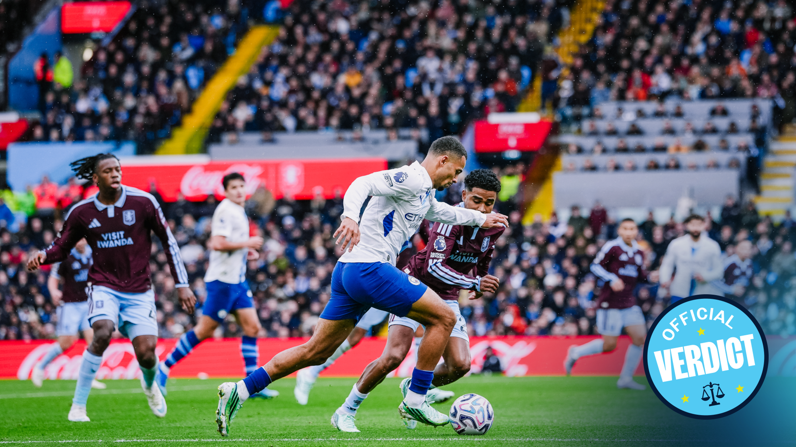 A soccer match between Aston Villa and Manchester City. Players are in action with Manchester City's player trying to control the ball, while Aston Villa's player is defending. The crowd is watching intently.