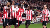 A group of Brentford FC players wearing their red and white striped jerseys celebrate on the field during a match.