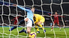 A Manchester City player in light blue makes a sliding goal-line clearance as Liverpool players in red look on at Etihad Stadium.