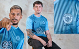 Esports players wearing a blue Manchester City jersey with esports logo.
