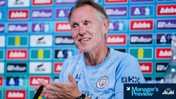 A person in a Manchester City shirt is clapping during a press conference. Behind them is a wall with various logos including Adobe. The image has a 'Manager's Preview' graphic in the corner.