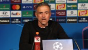 A man is speaking at a press conference with a UEFA Champions League backdrop and various sponsor logos. A Gatorade bottle is on the table in front of him.