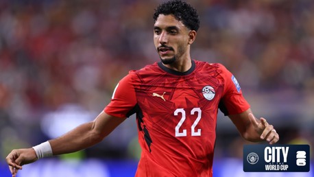 A football player in a red Egyptian national team jersey with Puma logo, number 22, wearing a white wristband at a World Cup event.